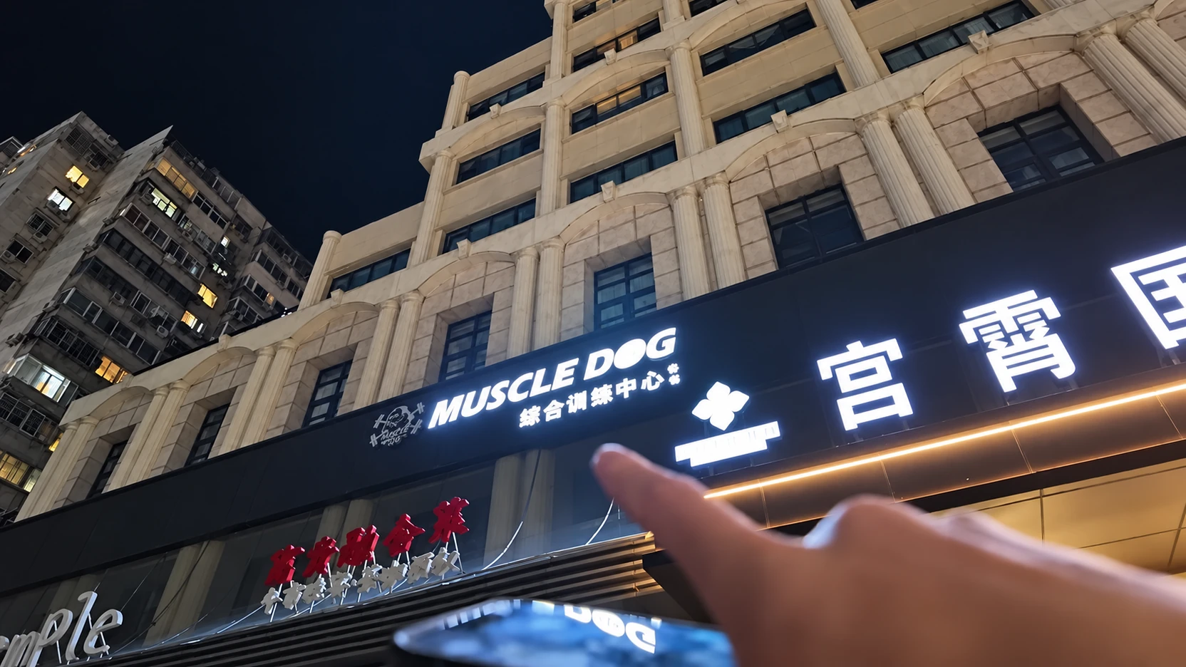 Letreiro iluminado da Muscle Dog na fachada de um prédio à noite em Pequim