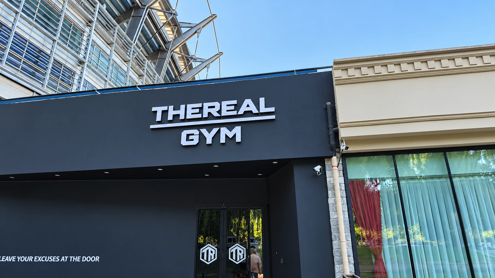 Fachada real da The Real Gym, em Pequim, com letreiro branco e entrada escura